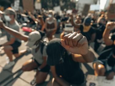protesters raising fists in air while kneeling