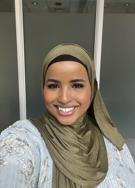 Halima smilling for a selfie. She is wearing a green hijab. 