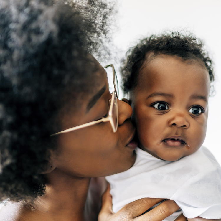 A Black mama kissing her baby on the cheek